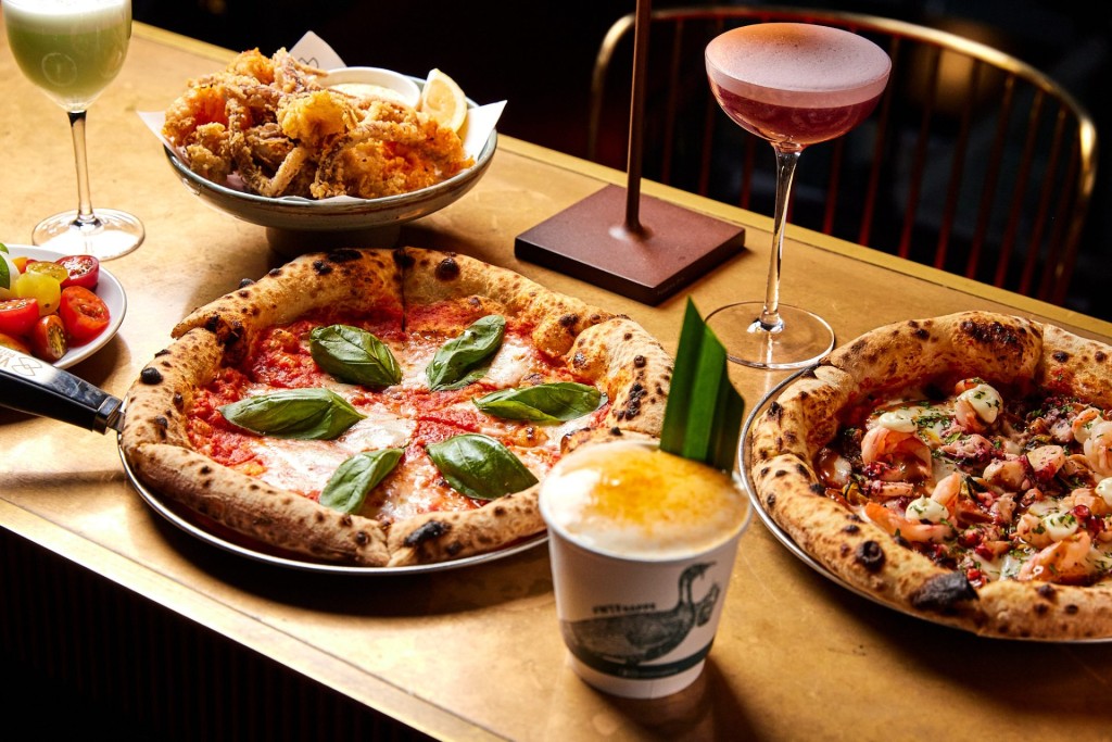 Neapolitan pizzas, fried calamari, and cocktails spread across the table at Vesu in Tsim Sha Tsui.