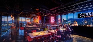 Diners in the neon-lit dining room with harbour views at night at Vesu Pizza Bar, Tsim Sha Tsui.